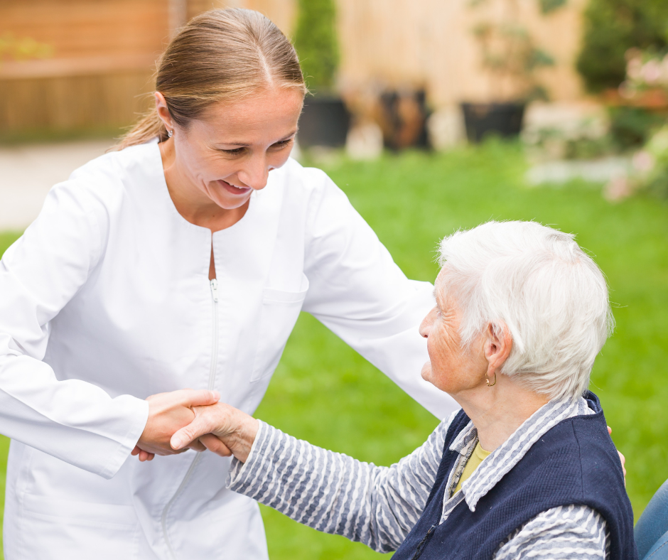 female health worker assists older woman seated in a chair