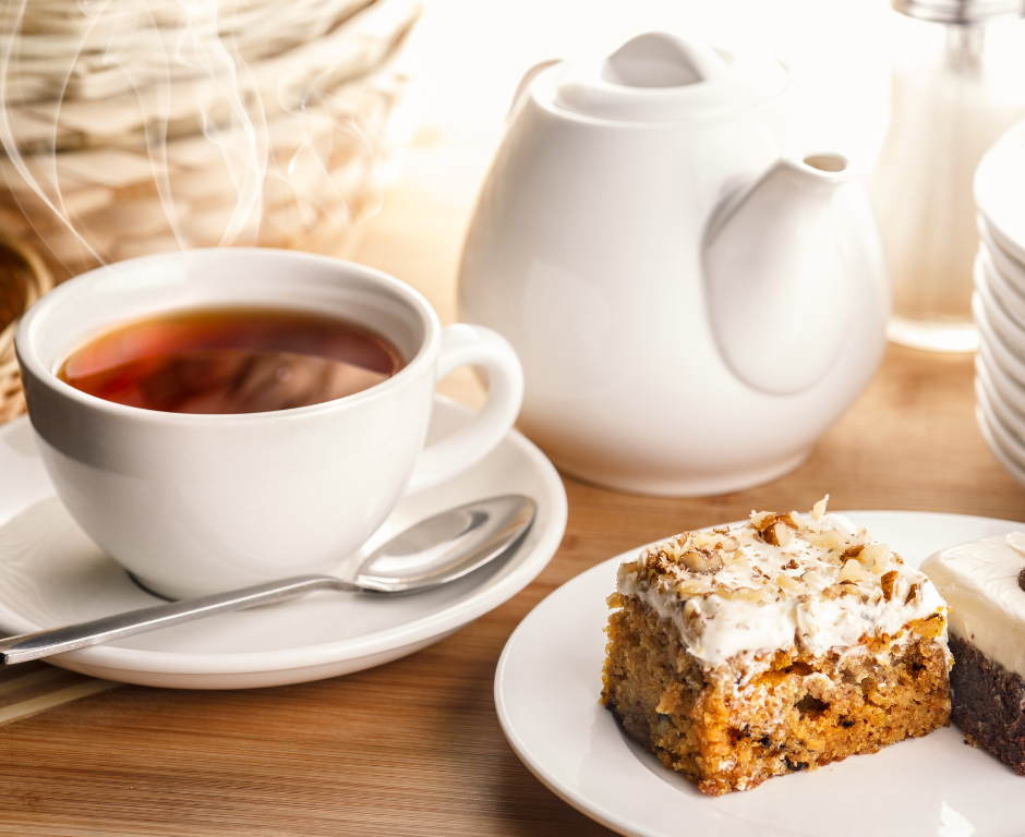 white teapot, steaming cup of black tea, carrot cake on a white plate